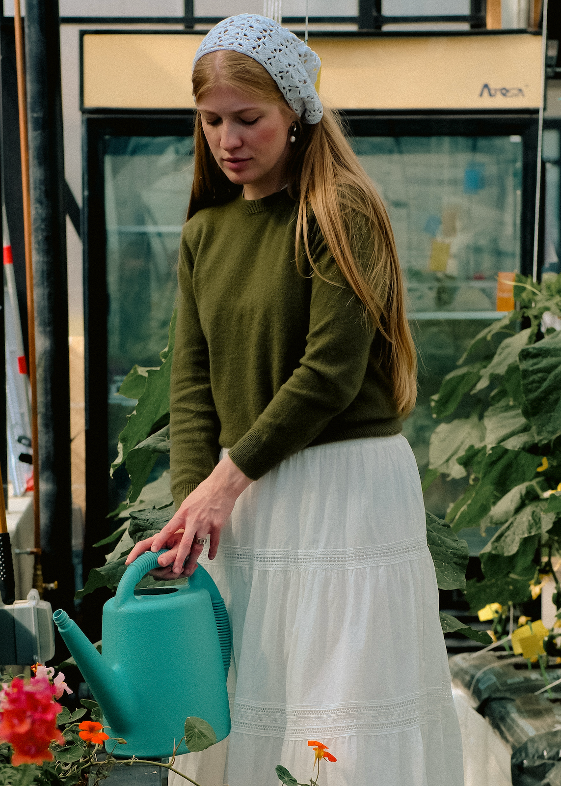 Woman in a greenhouse holding a blue watering can