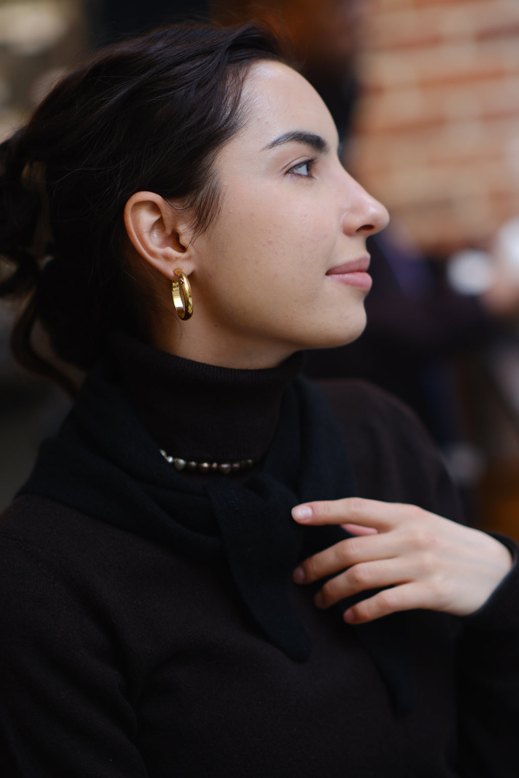 Woman wearing a black 100% cashmere triangle scarf styled over a black turtleneck.