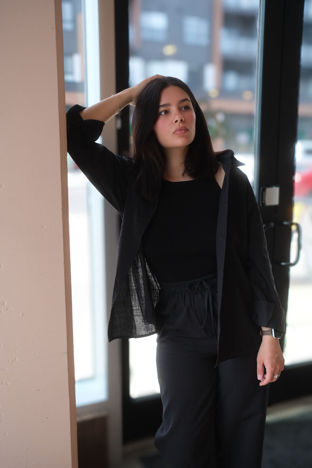 Woman in black outfit standing indoors with a blurred background