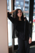 Woman in black outfit standing indoors with a blurred background