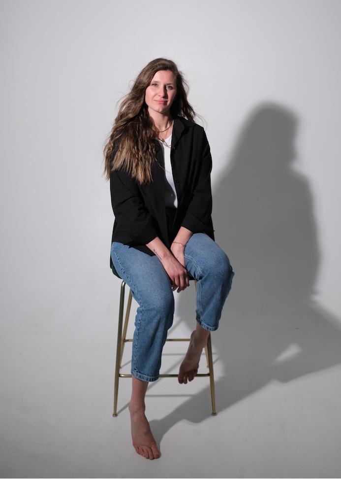 Woman sitting on a stool against a white background