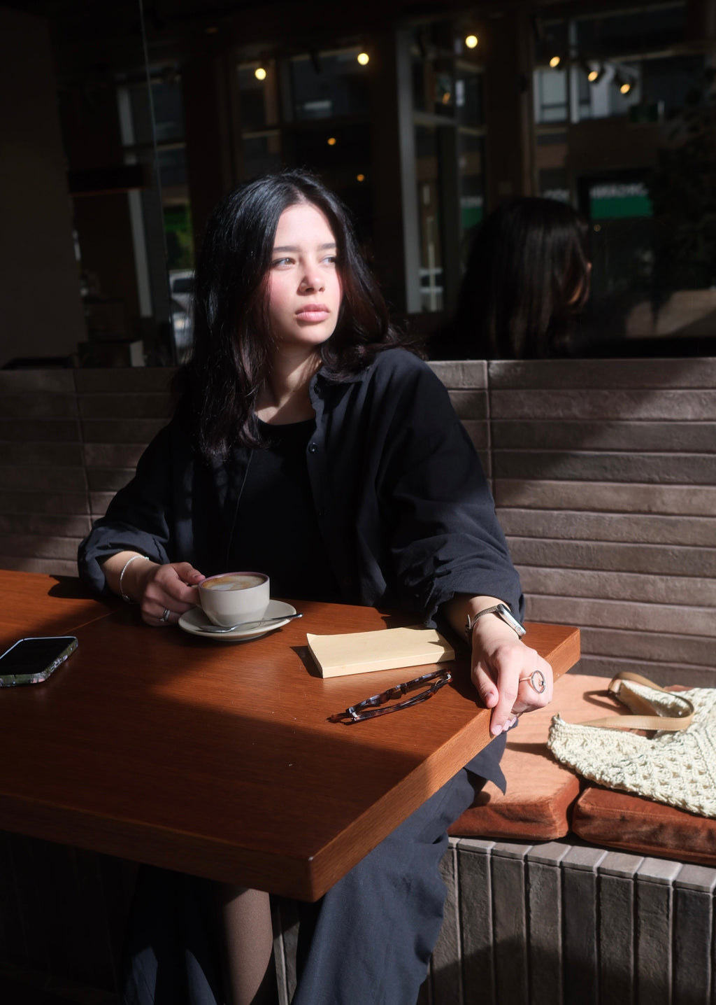 Woman sitting at a table in a cafe with a cup of coffee