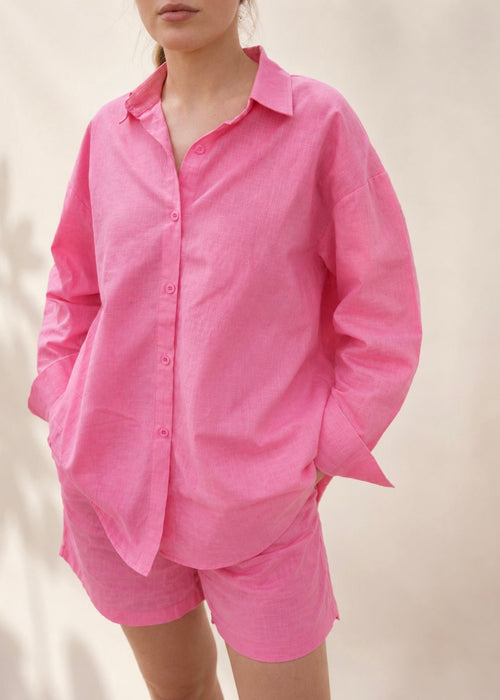 Person wearing a pink shirt and shorts set on a plain background