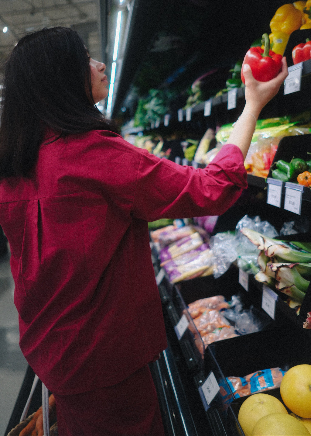 Person shopping in a grocery store, selecting items from the shelves.