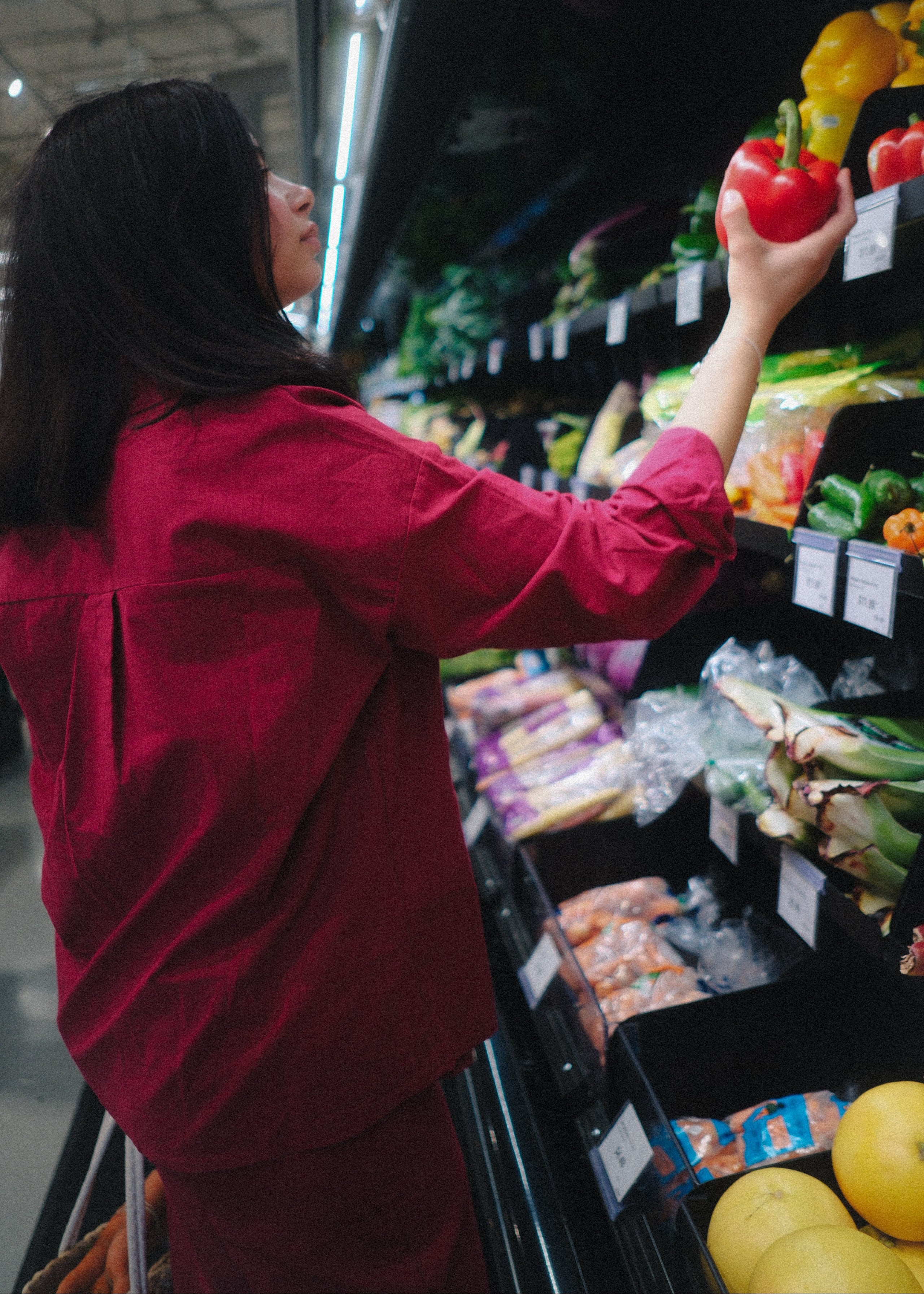 Person shopping in a grocery store, selecting items from the shelves.