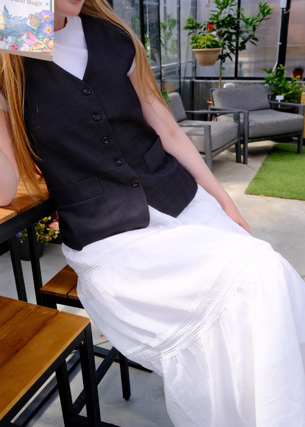 Person wearing a black coat and white dress in an indoor setting with furniture and decor.