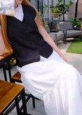 Person wearing a black coat and white dress in an indoor setting with furniture and decor.