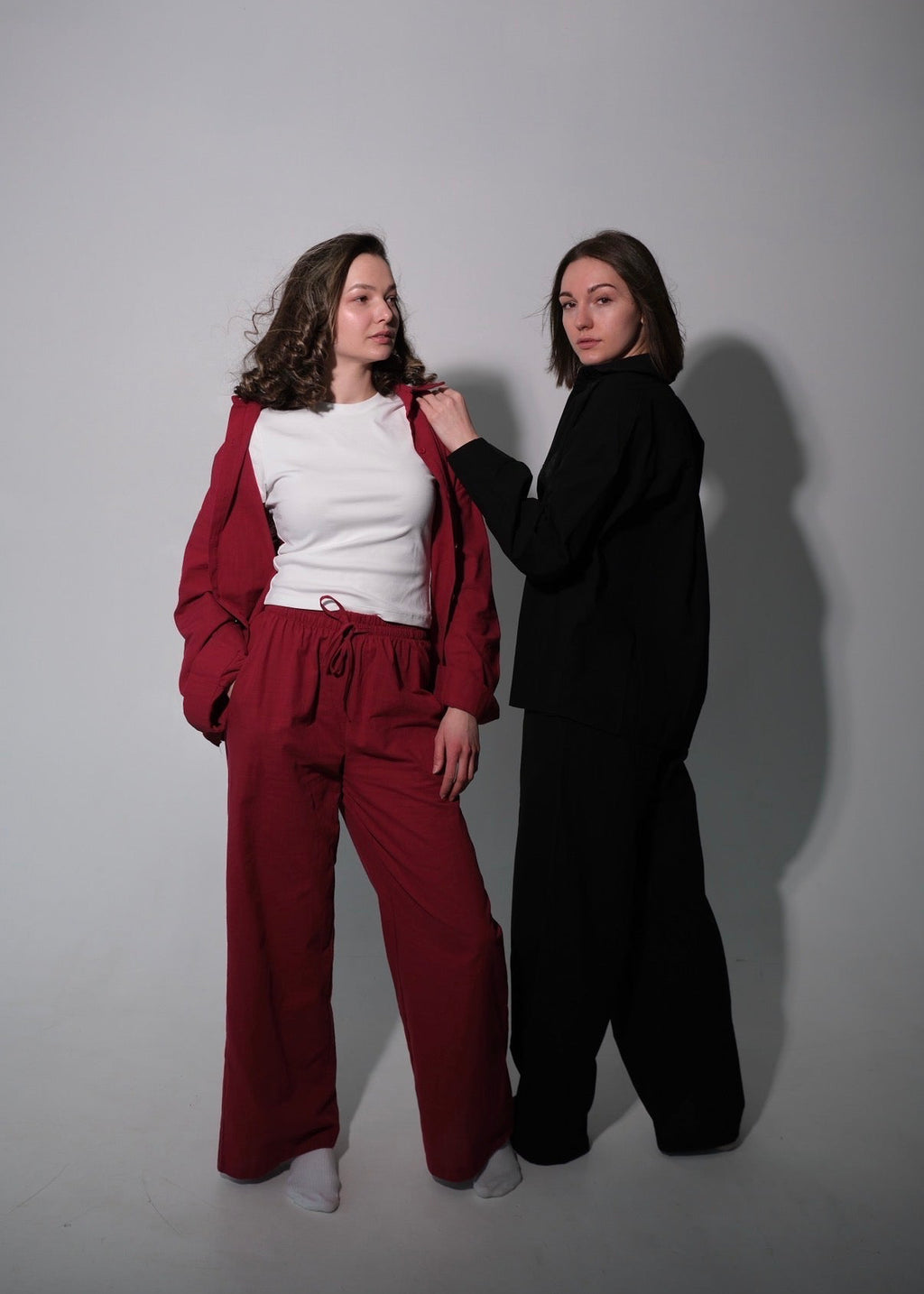 Two people wearing red and black outfits against a plain background