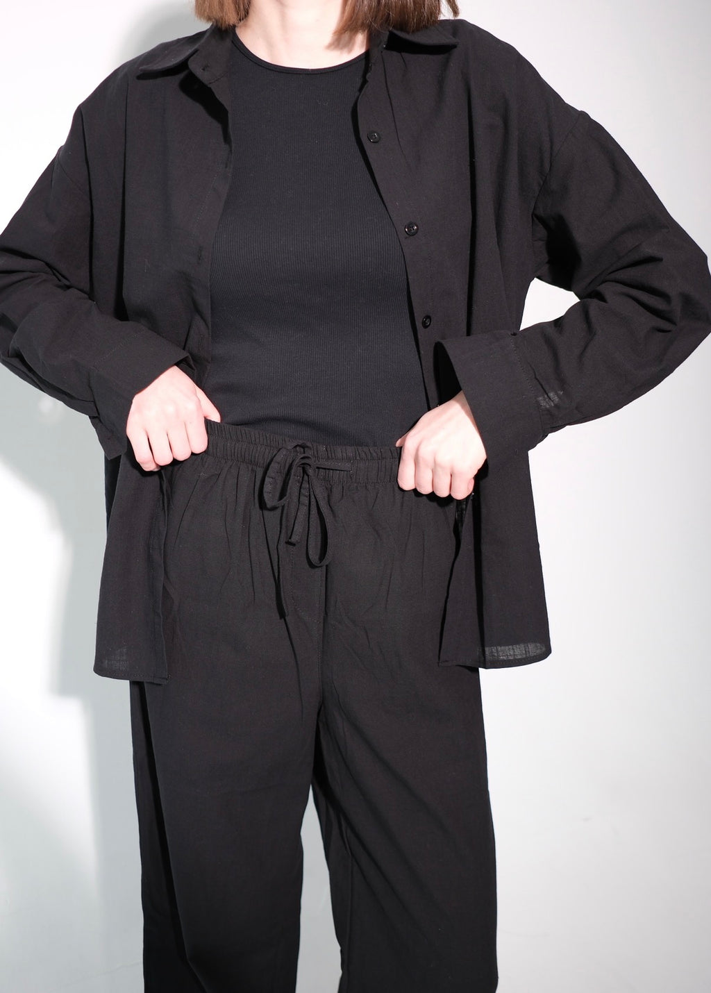 Person wearing a black outfit with a jacket and pants on a white background