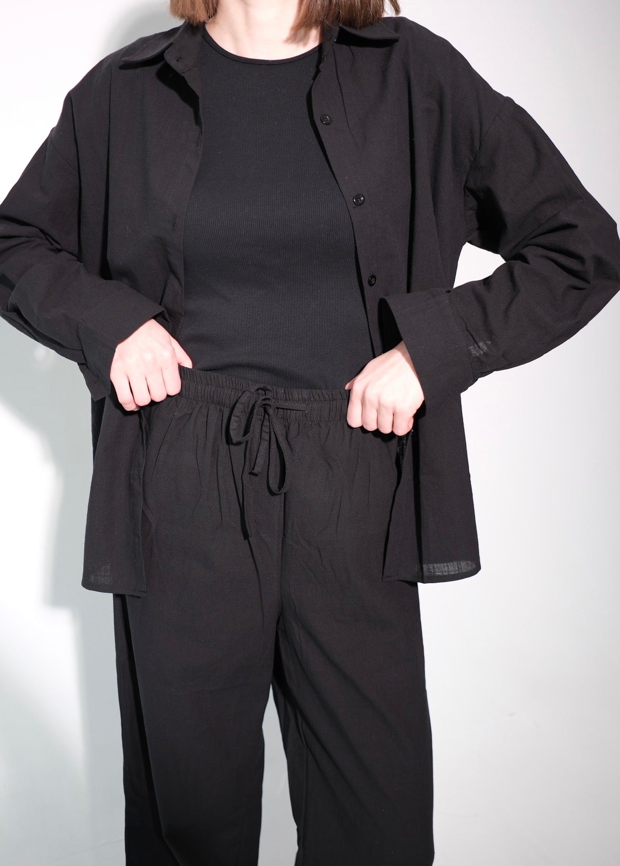 Person wearing a black outfit with a jacket and pants on a white background