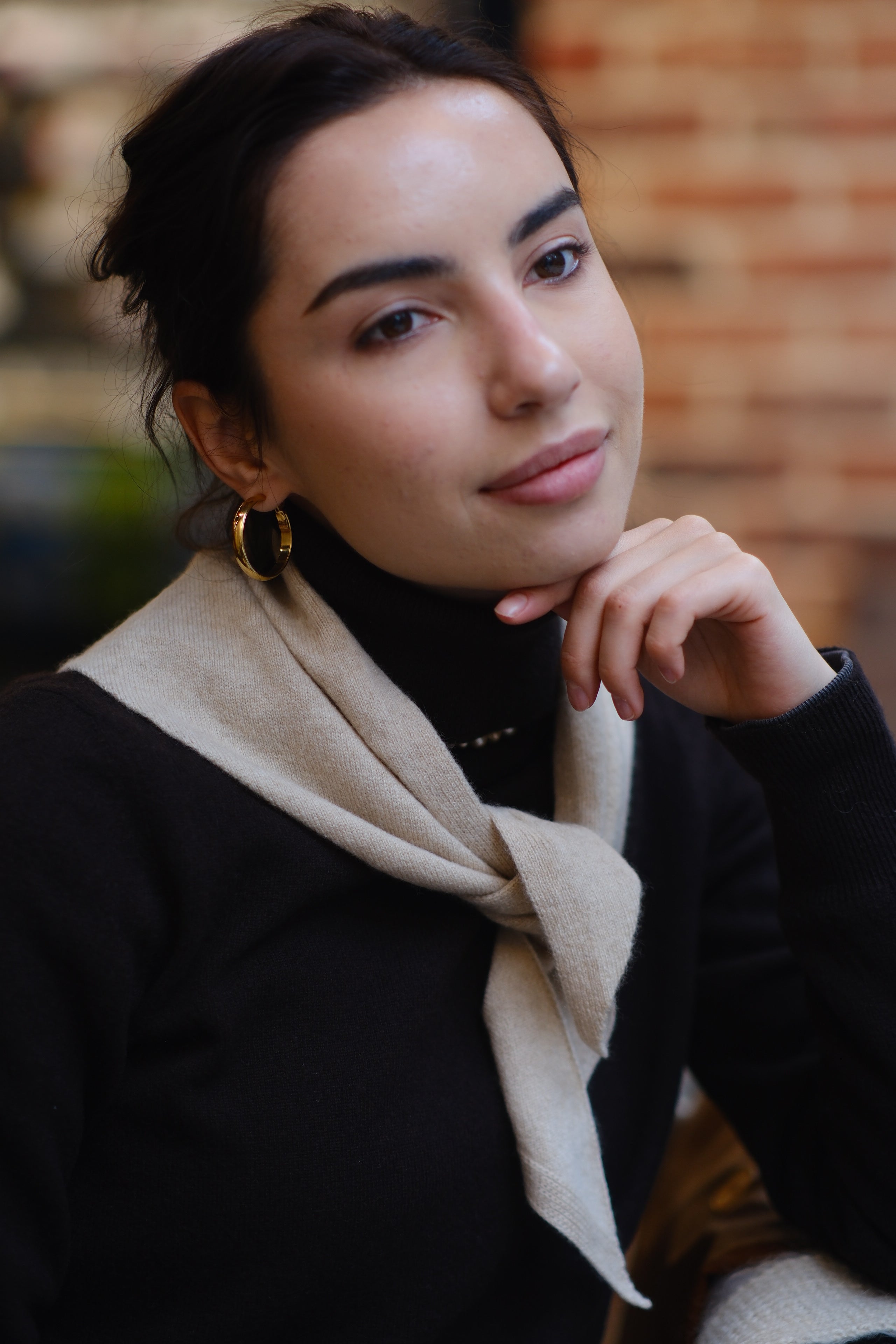 Woman wearing a beige 100% cashmere triangle scarf styled as an elegant neck accessory.