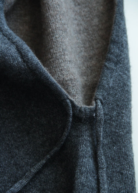 Close-up of a dark charcoal gray knit garment, showing the texture of the outer fabric and a lighter taupe-gray inner lining.