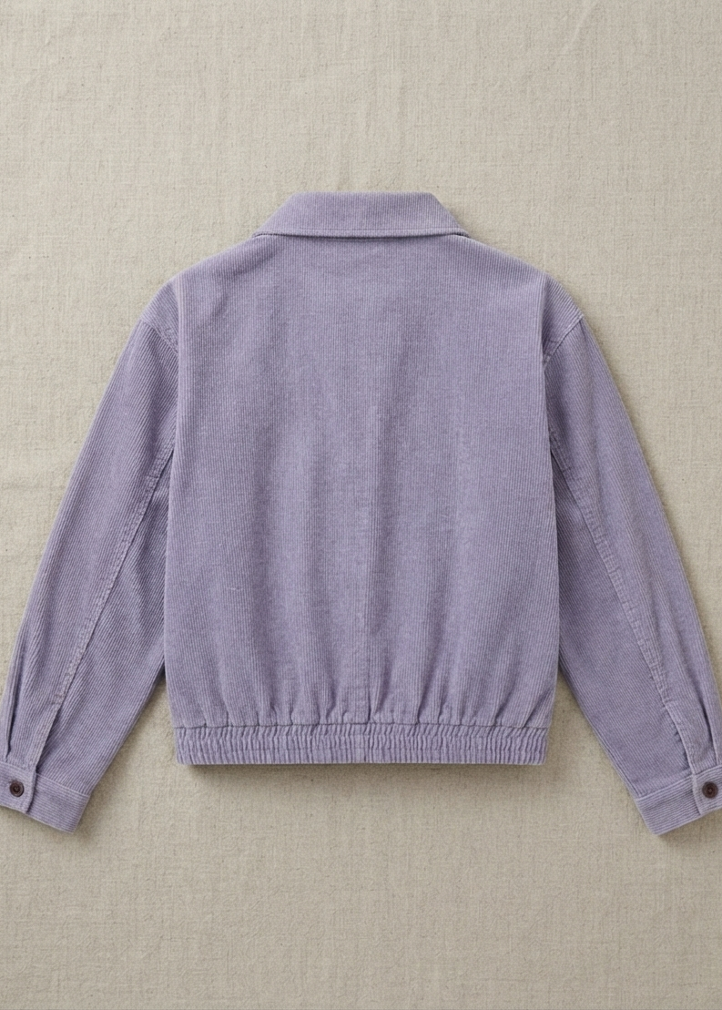 A light purple corduroy jacket shown from the back, laid flat on a textured beige fabric background.