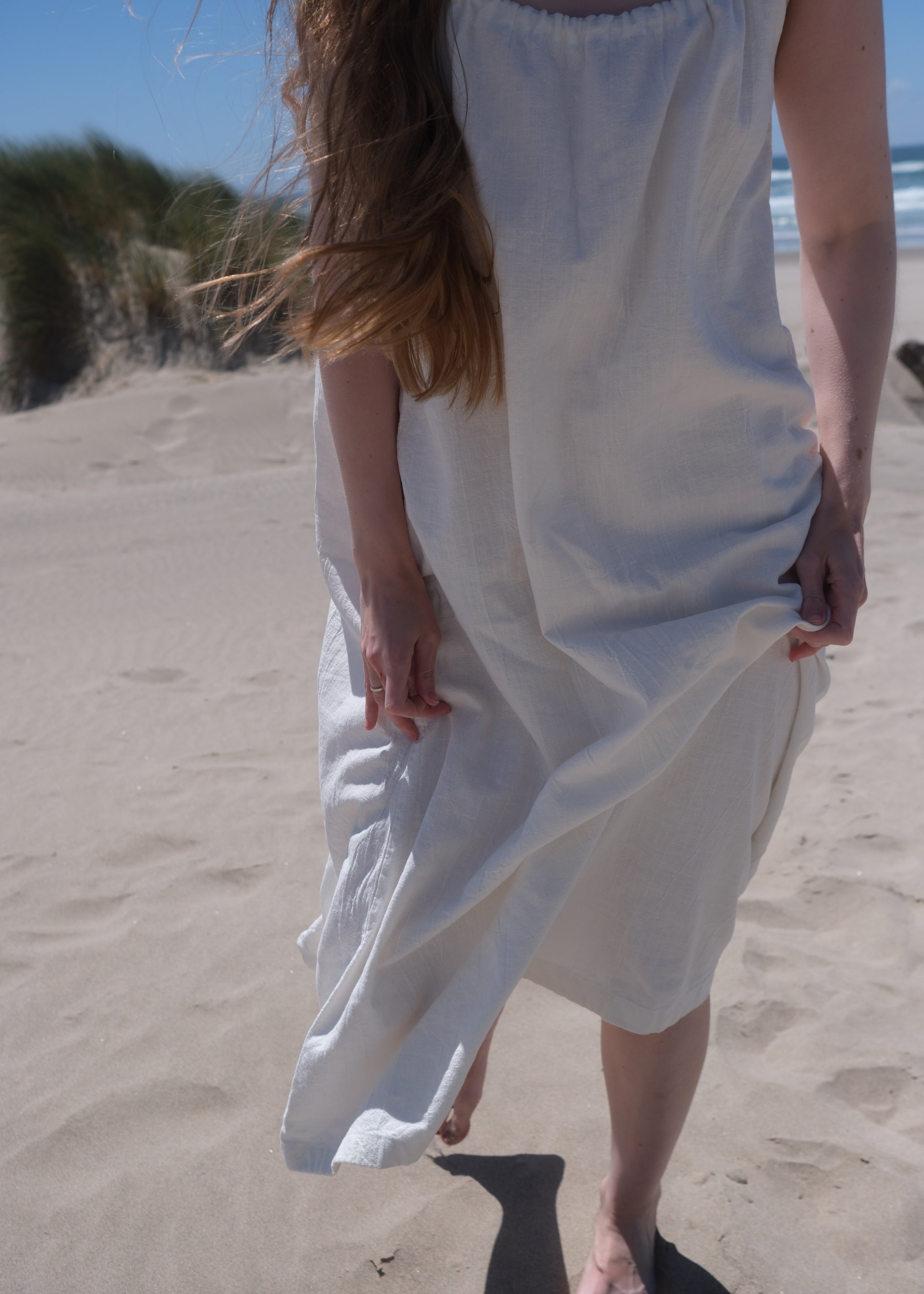 Person holding a white dress on a sandy beach
