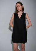 Woman wearing a black sleeveless dress against a plain background