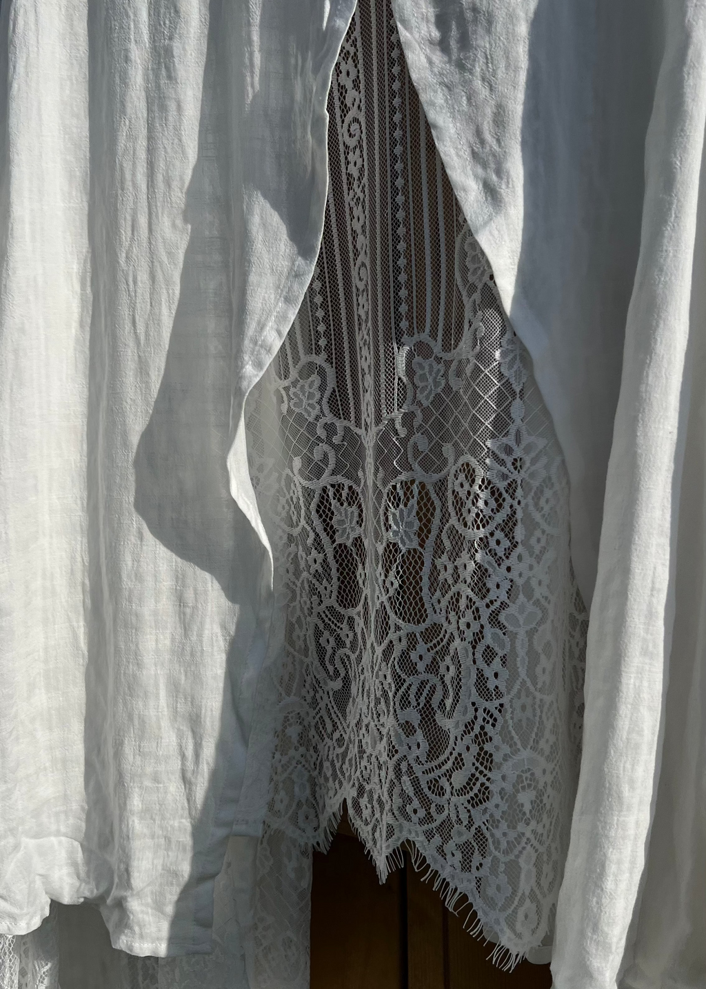 White lace garment with sheer fabric draped over it