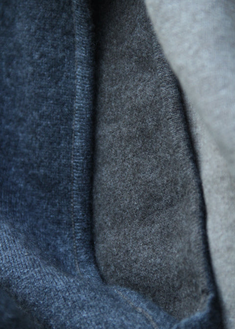 Close-up of folded knit fabric in dark blue and heather gray tones, showing the texture and ribbed edge of the material.