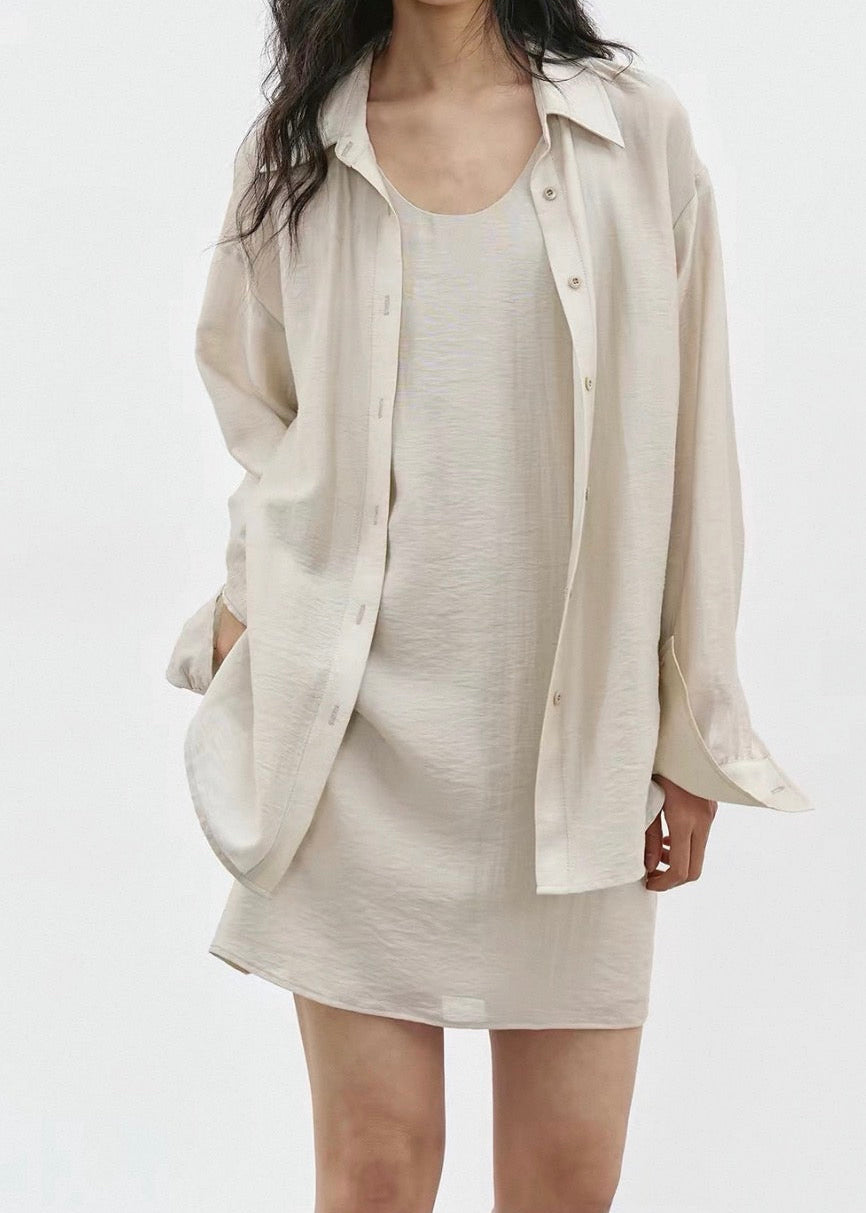 Woman wearing a beige shirt over a dress on a white background