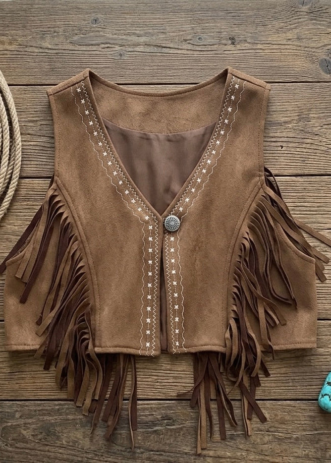 Brown suede vest with fringe and buttons on a wooden surface with rope and turquoise stone.