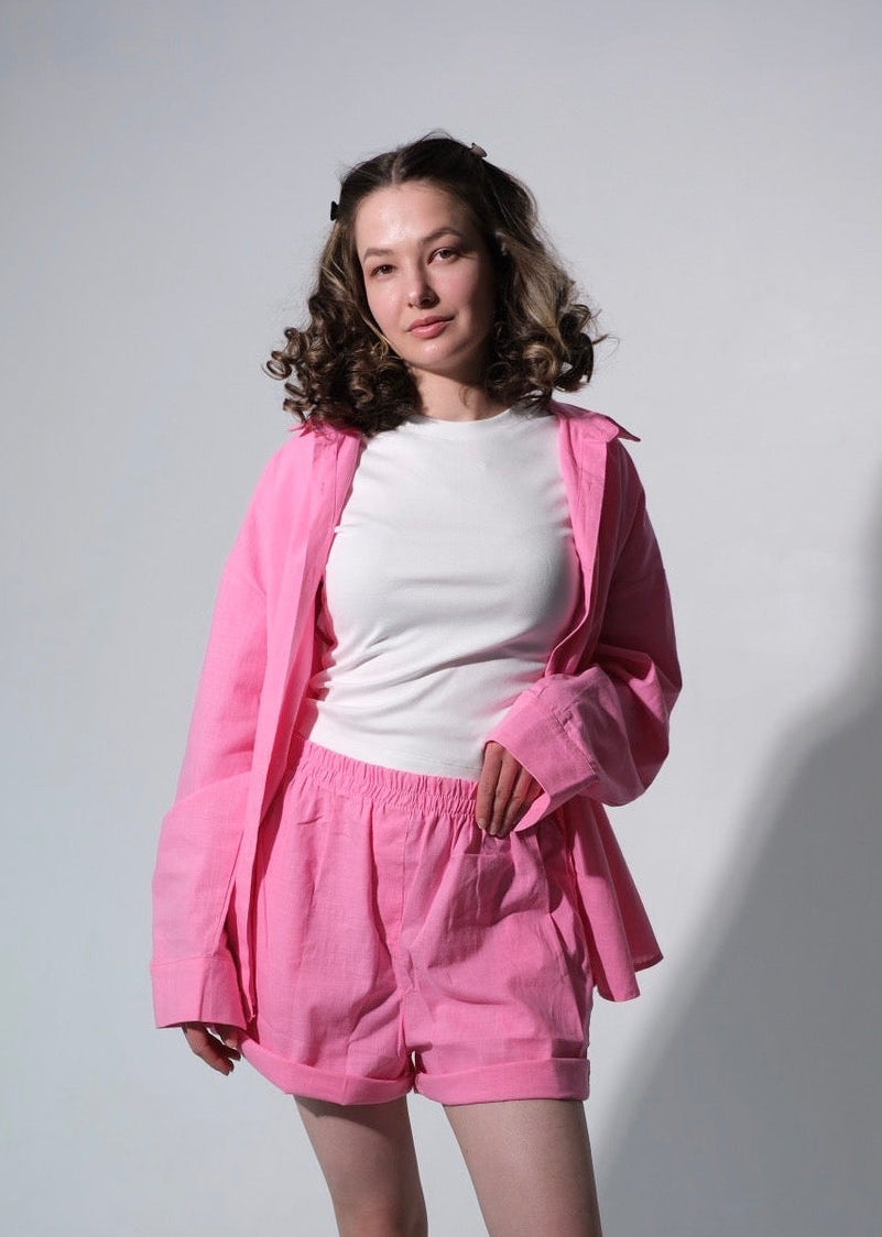 Person wearing a pink tracksuit and white shirt on a plain background