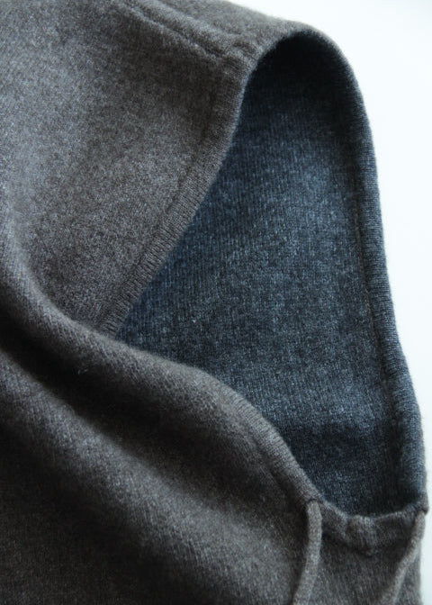 Close-up of a dark gray knit fabric hood or cowl with a contrasting dark blue-gray inner lining, shown against a plain white background.