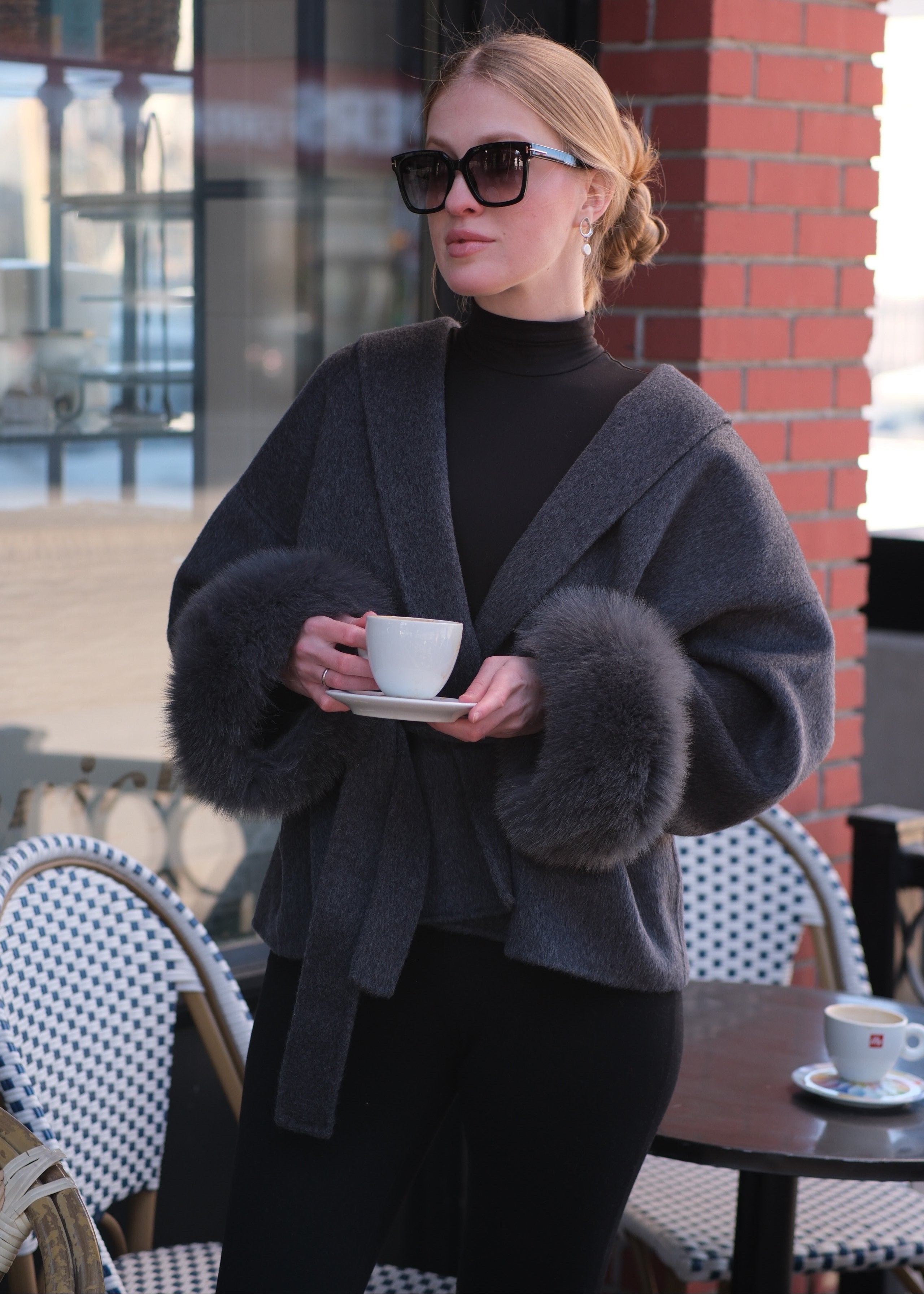 Person wearing a dark coat with fur collar in an urban setting
