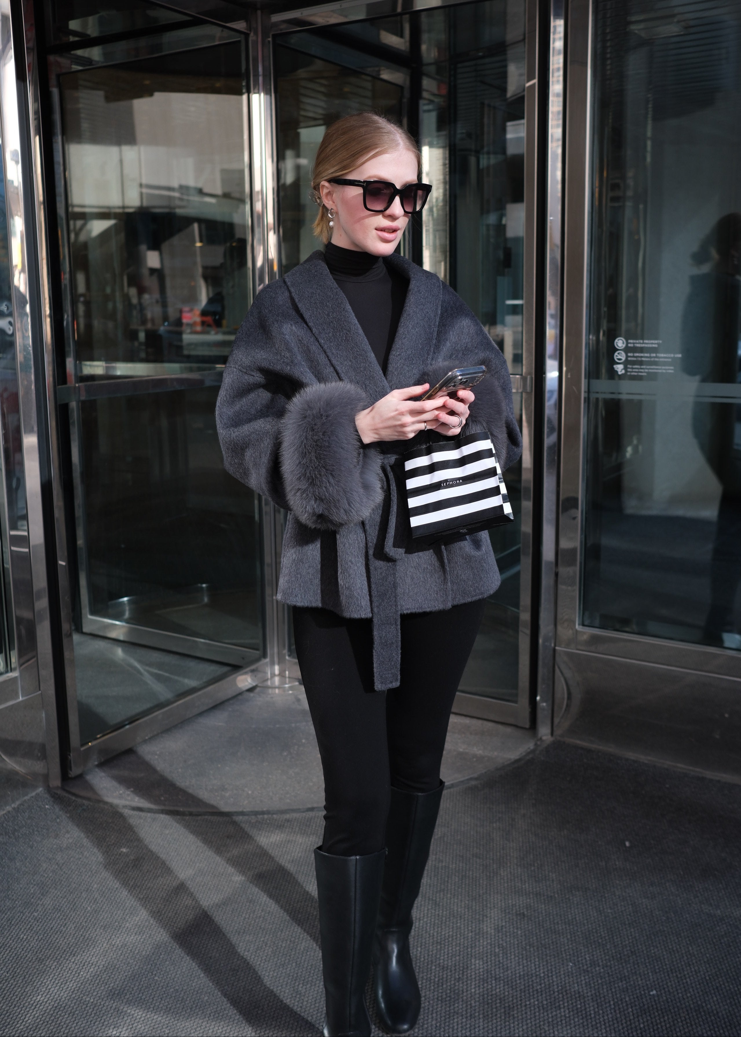 Person holding a black and white striped bag in a reflective surface setting