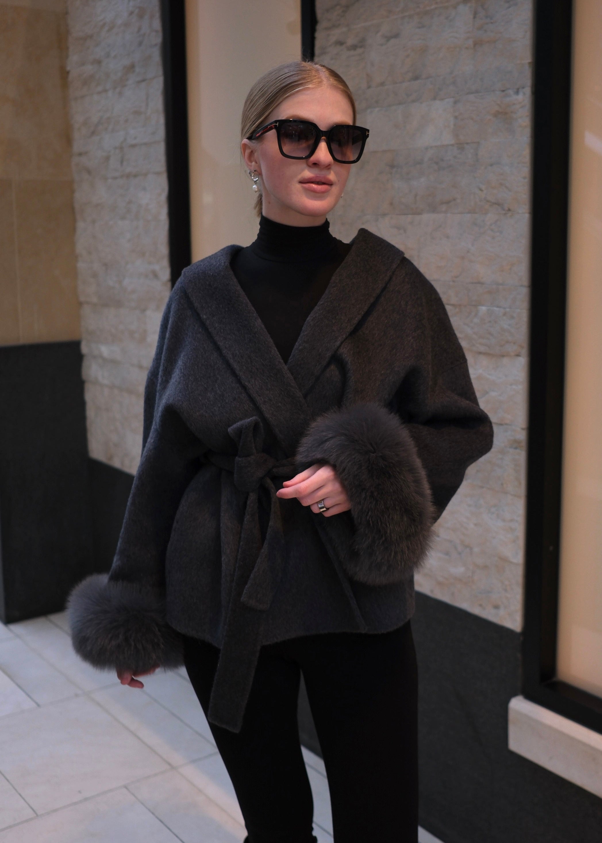 Woman wearing a dark coat with fur trim in an urban setting