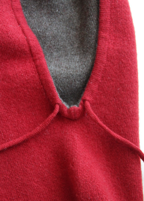 Close-up of a red knit garment with a gray inner lining or underlayer visible at the neckline.