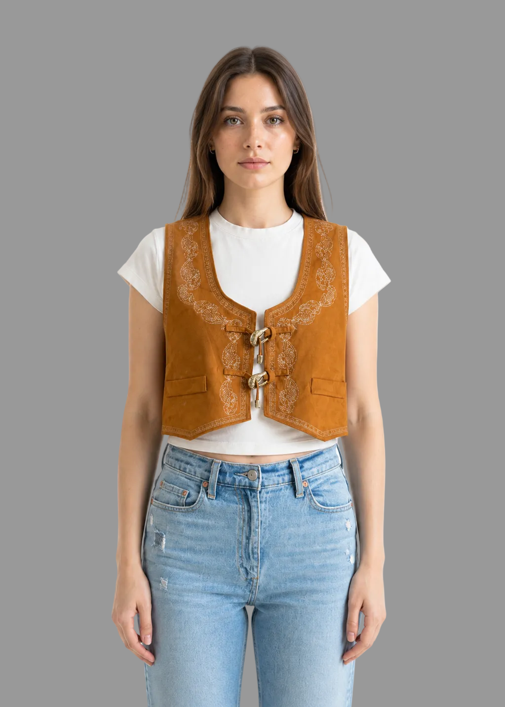 Woman wearing a mustard yellow vest over a white shirt with blue jeans on a white background