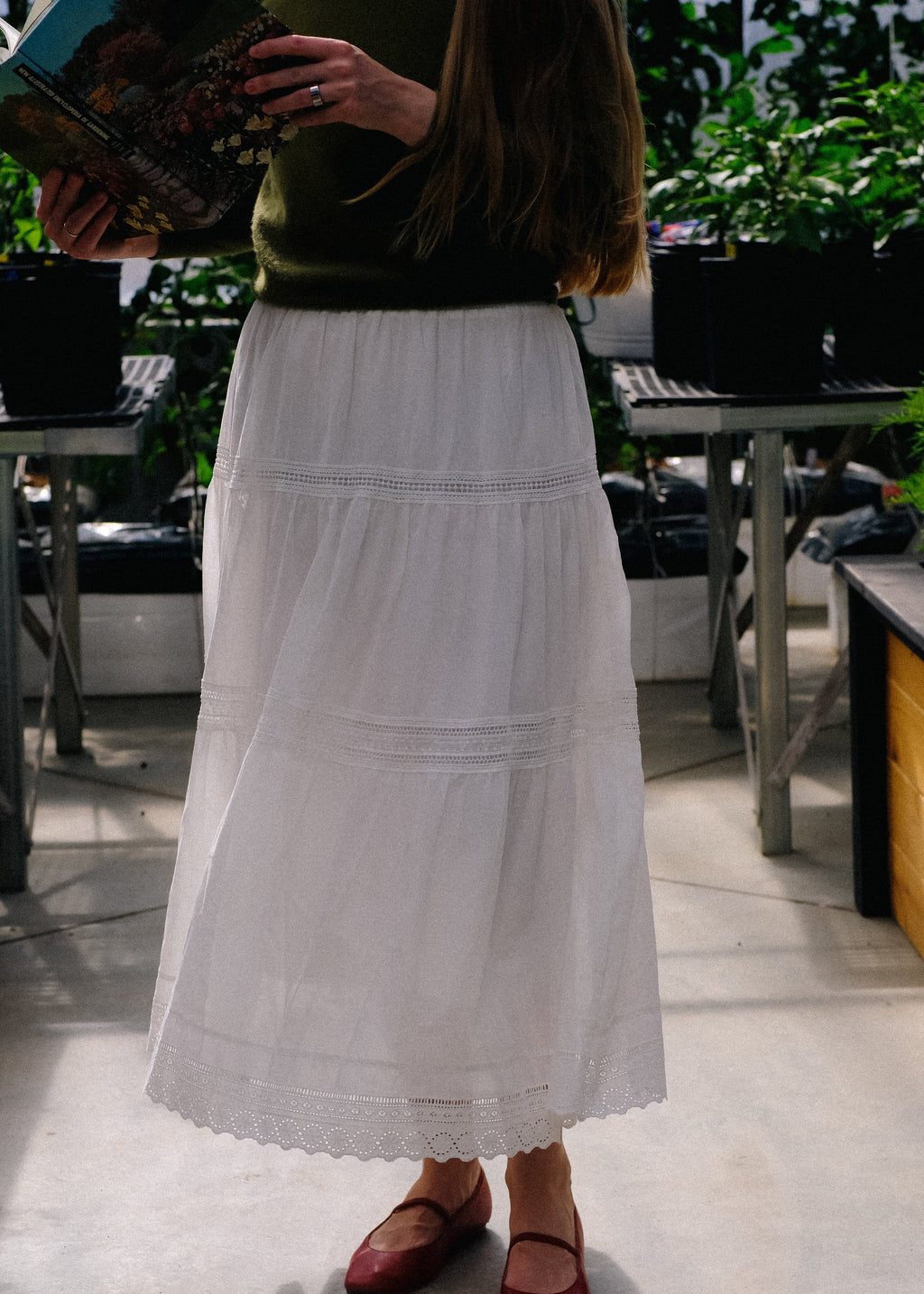 Person wearing a white skirt and red shoes standing outdoors.