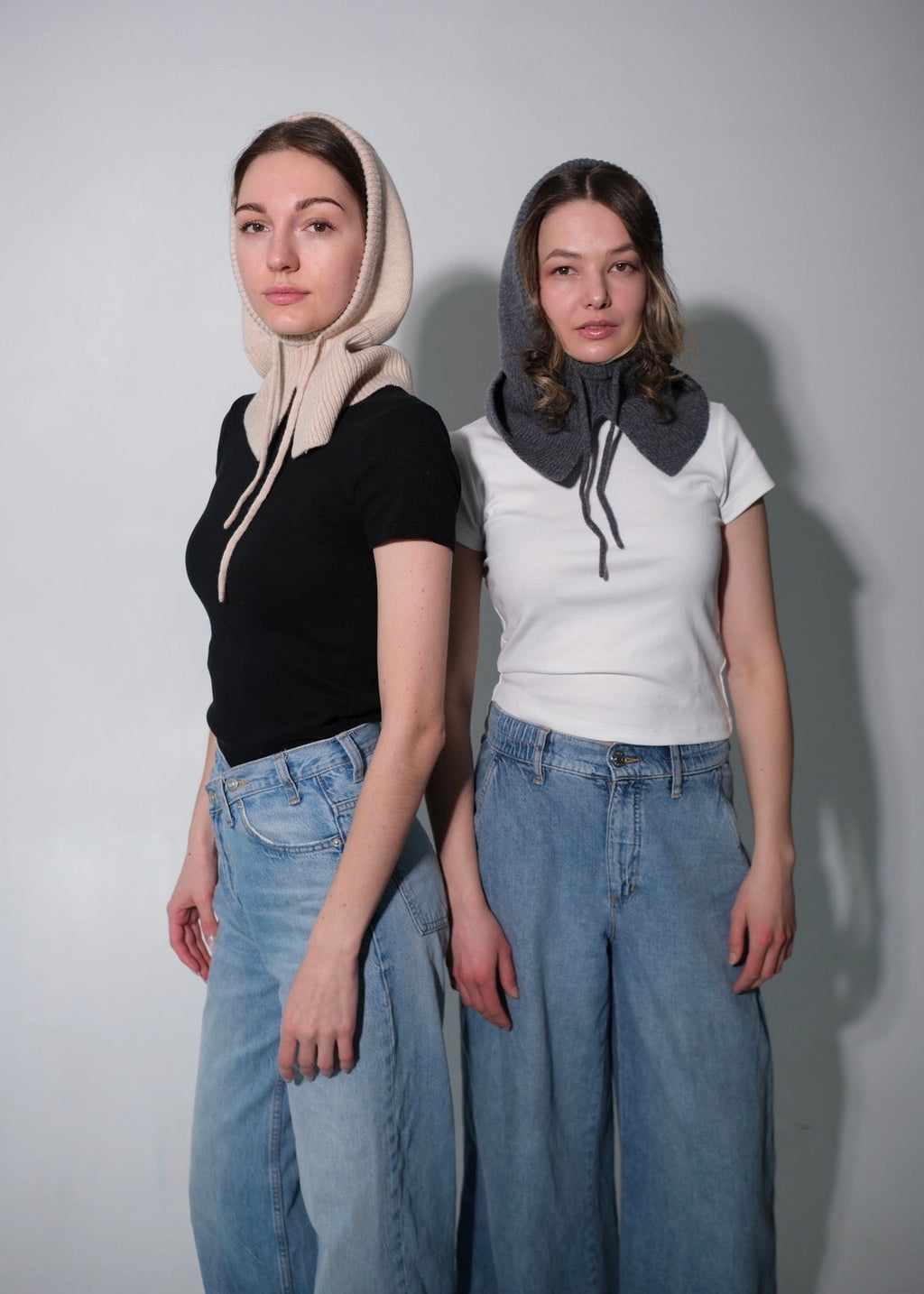 Two women wearing hooded hats with different color schemes against a plain background
