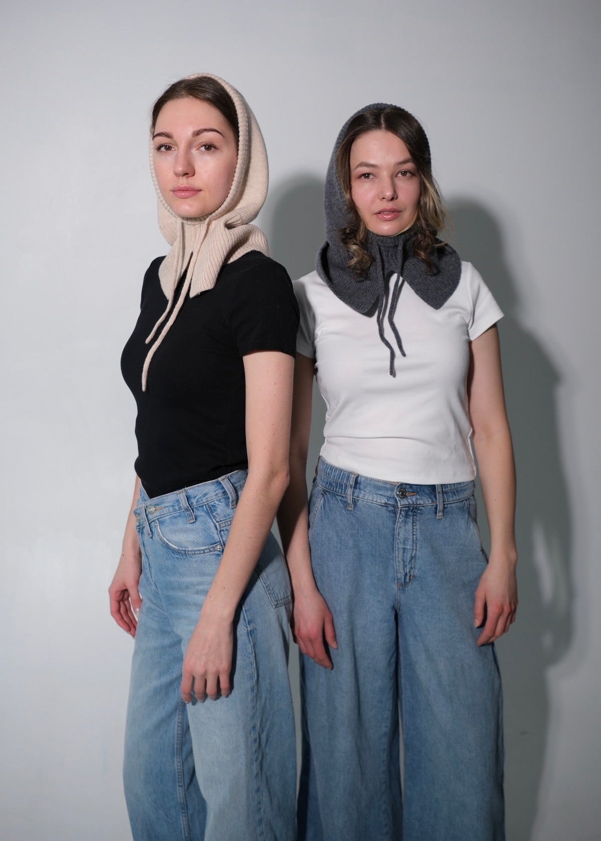 Two women wearing hooded hats with different color schemes against a plain background
