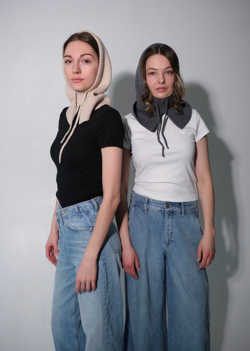 Two women wearing hooded hats with different color schemes against a plain background