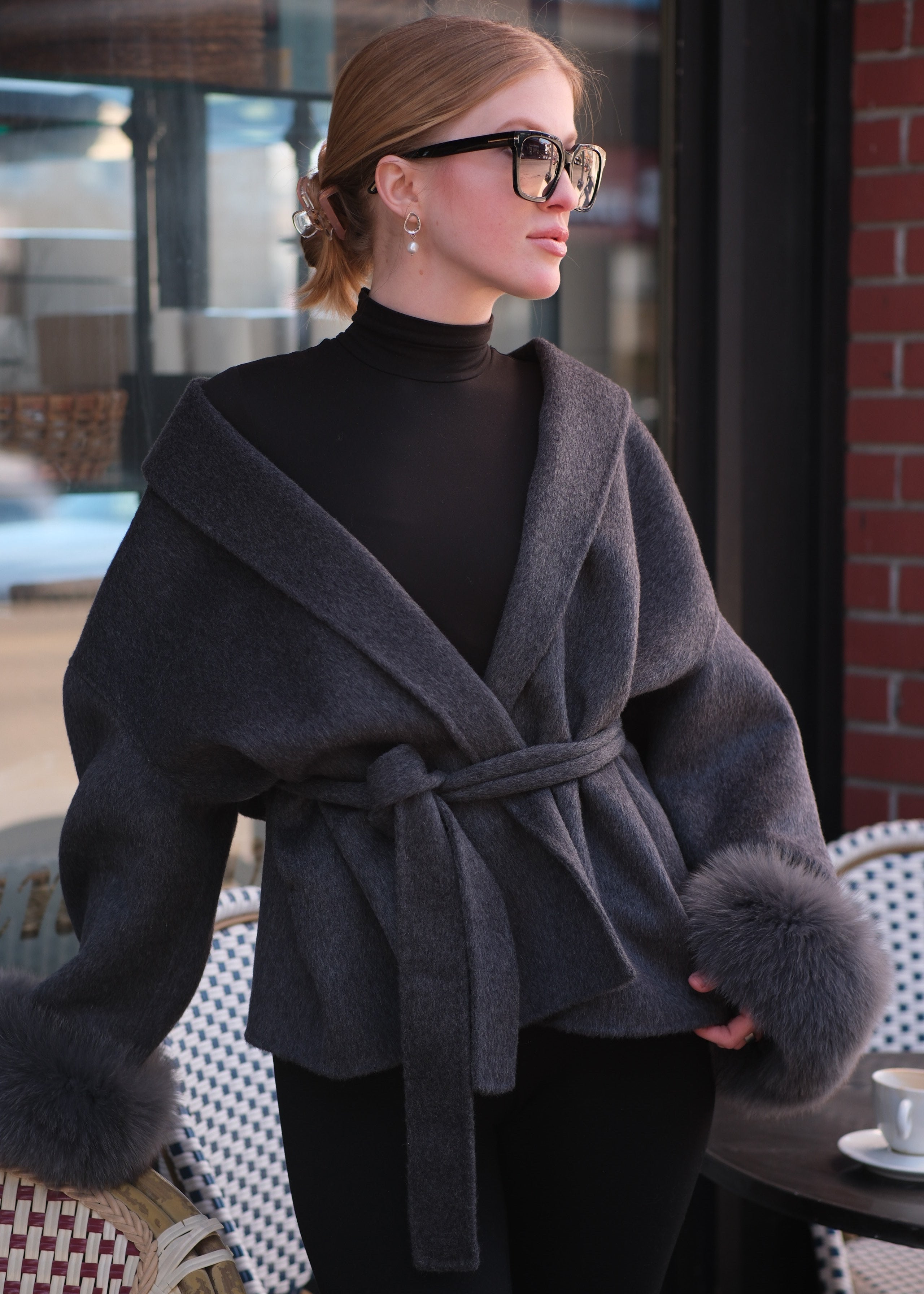 Person wearing a dark coat with fur trim in an indoor setting