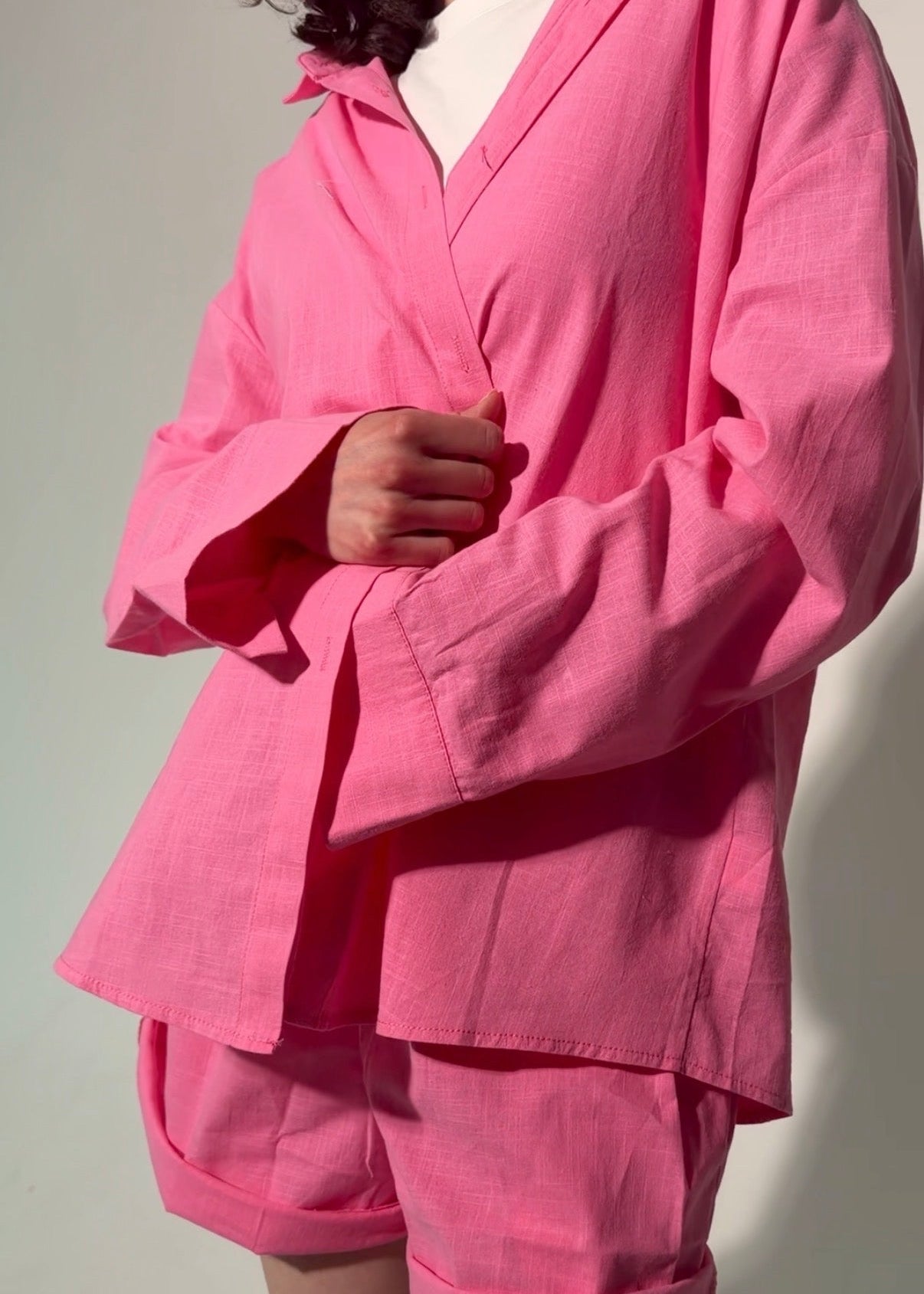 Person wearing a bright pink outfit with a jacket and shorts on a plain background